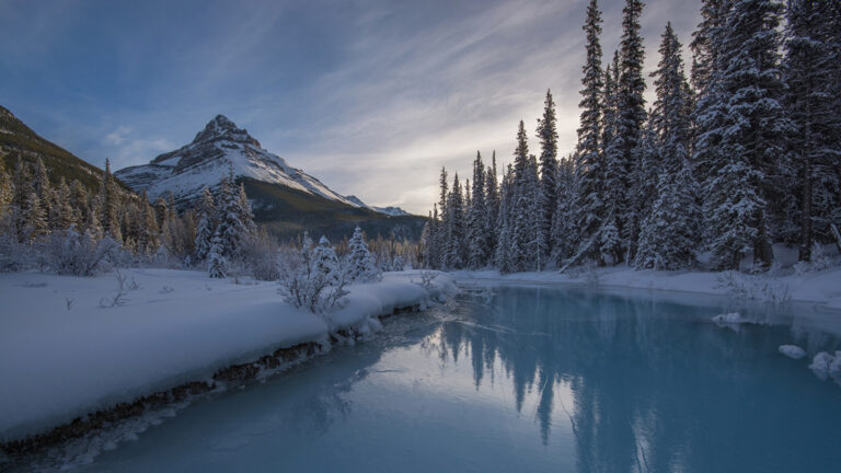 Un lac gelé avec des arbres et une montagne recouvert de neige